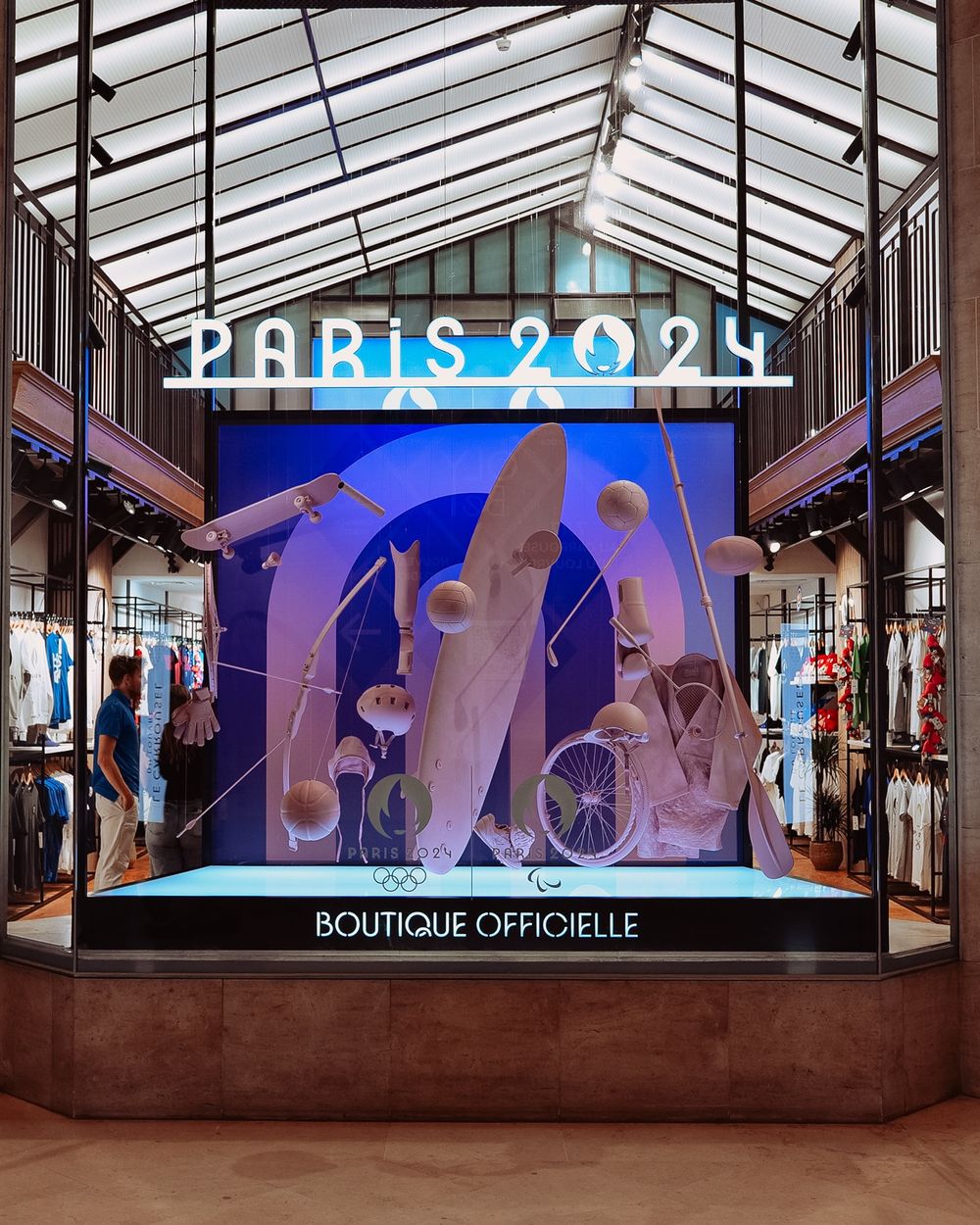 Vitrine de la boutique officielle Paris 2024, mise en scène d'équipements sportifs
